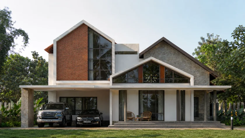 Saji Residence: a tall glazed gable, white walls and a sheltered entrance.